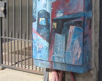 A street electrical box decorated with a picture of city composed from several high floors buildings of different colors