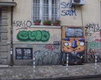 A street electrical box decorated with a cartoon-like picture of a human in a suit and with large orange head